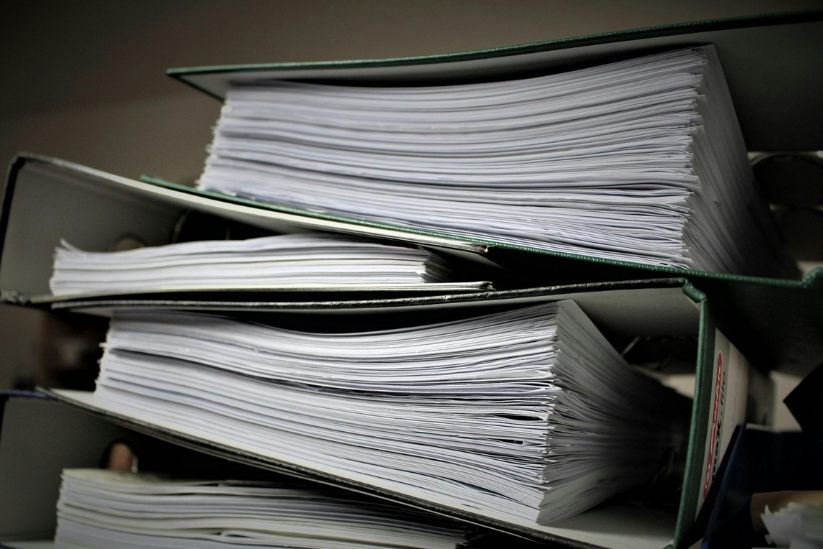 A stack of binders with paper.